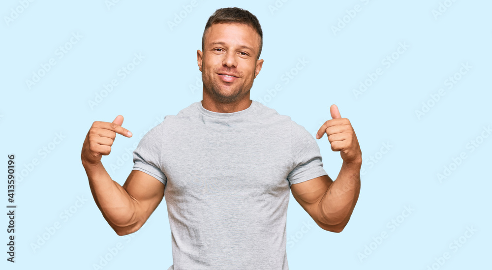 Handsome muscle man wearing casual grey tshirt looking confident with smile on face, pointing oneself with fingers proud and happy.