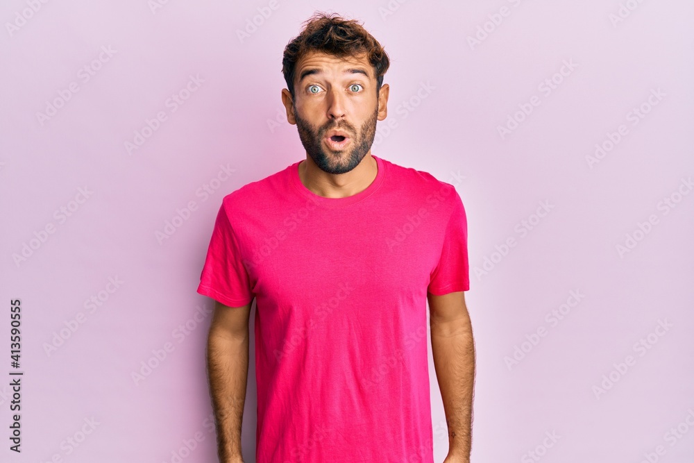 Handsome man with beard wearing casual pink tshirt over pink background scared and amazed with open mouth for surprise, disbelief face Handsome man with beard wearing casual pink tshirt over pink background scared and amazed with open mouth for surprise, disbelief face