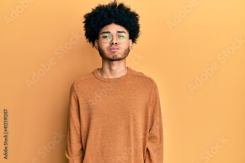 Young african american man with afro hair wearing casual winter sweater puffing cheeks with funny face. mouth inflated with air, crazy expression. © Krakenimages.com