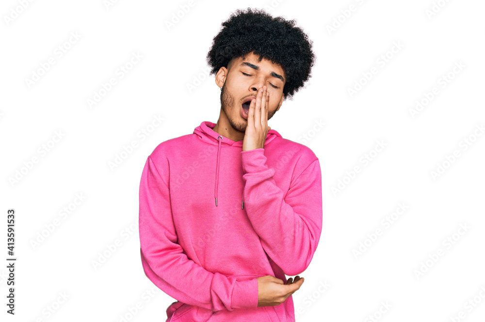 Young african american man with afro hair wearing casual pink sweatshirt bored yawning tired covering mouth with hand. restless and sleepiness. Young african american man with afro hair wearing casual pink sweatshirt bored yawning tired covering mouth with hand. restless and sleepiness.