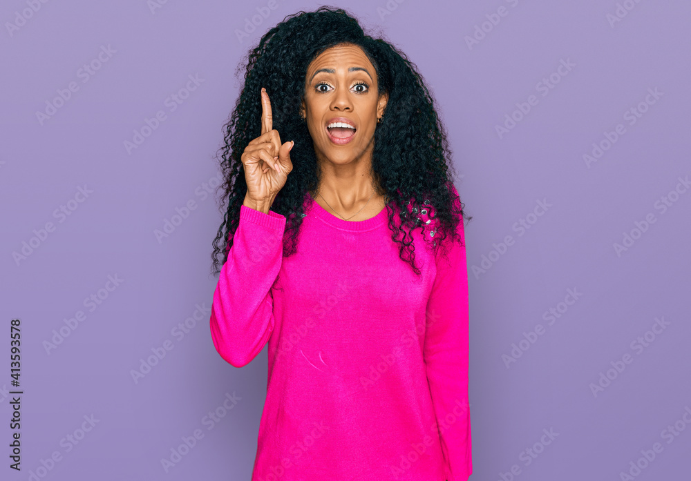 Middle age african american woman wearing casual clothes pointing finger up with successful idea. exited and happy. number one. Middle age african american woman wearing casual clothes pointing finger up with successful idea. exited and happy. number one.