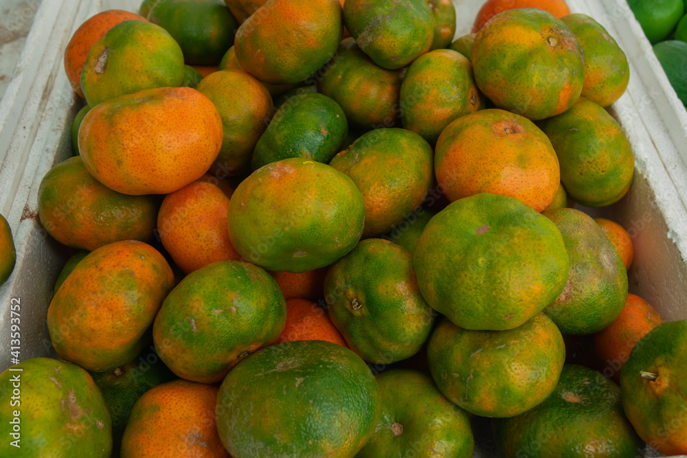 Group of freshly grown orange and green mandarins inside a white box