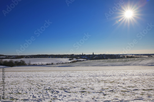 the catholic and protestant church of homberg in winter with snow and blue sky and sun 