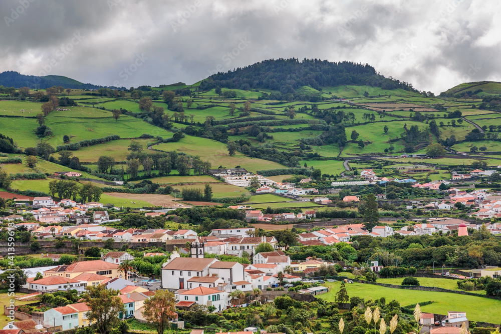 Fresh green nature with fields, meadows. pastures and a small village. Cloudy rainy sky. Sao Migue Island, Portugal.