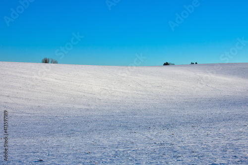 snowy farmland with sunlight and blue sky