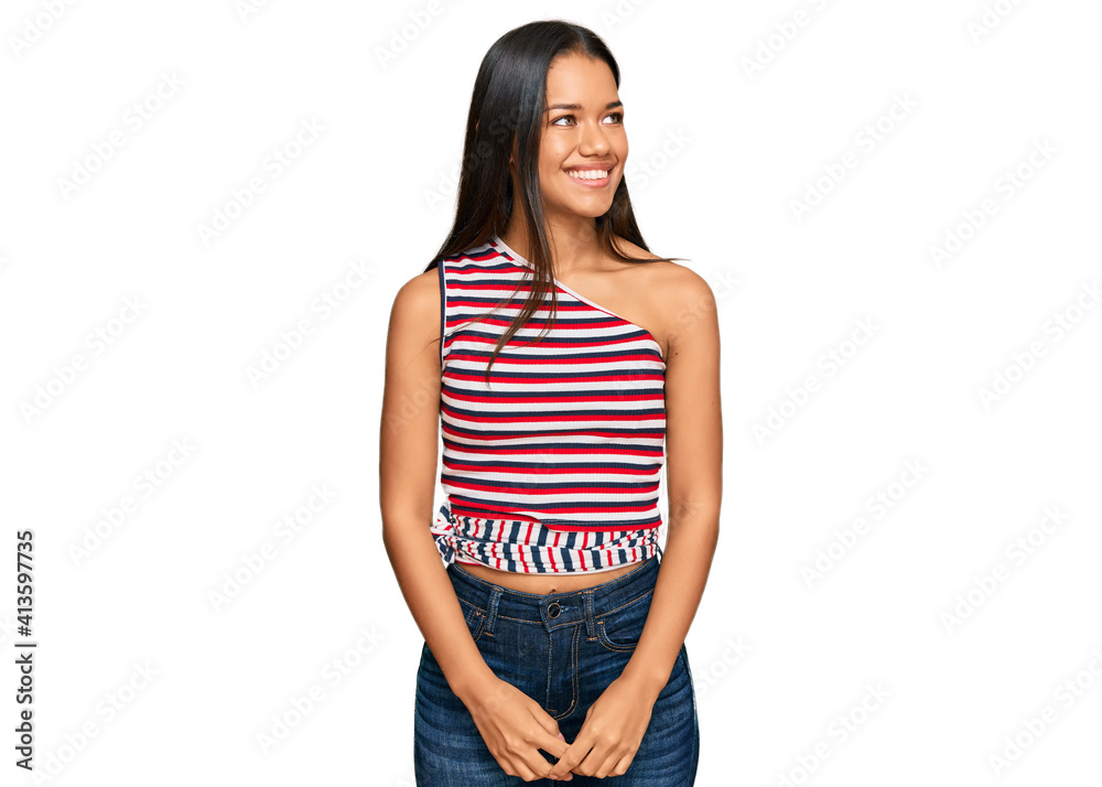 Fototapeta premium Beautiful hispanic woman wearing casual clothes looking away to side with smile on face, natural expression. laughing confident.