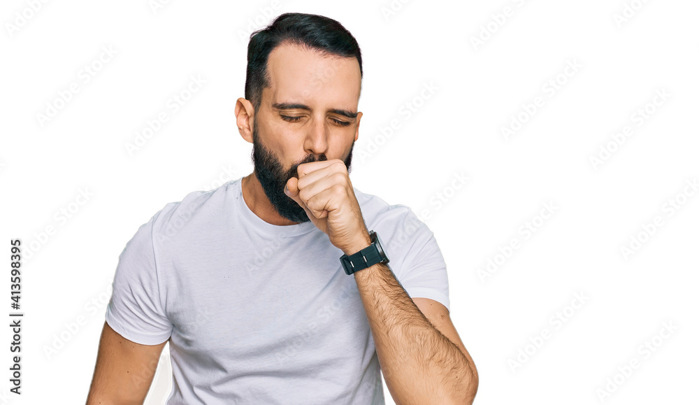 Young man with beard wearing casual white t shirt feeling unwell and coughing as symptom for cold or bronchitis. health care concept. Young man with beard wearing casual white t shirt feeling unwell and coughing as symptom for cold or bronchitis. health care concept.