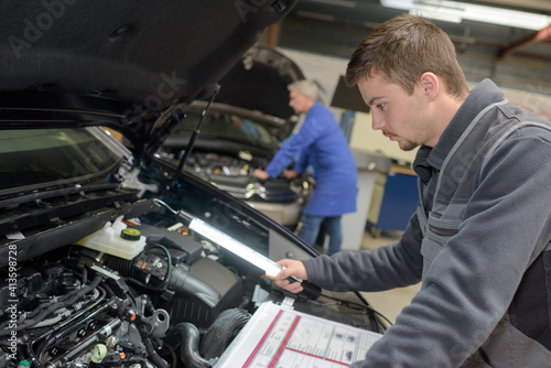 young mechanic working on car engine