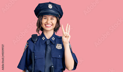 Young beautiful girl wearing police uniform showing and pointing up with fingers number three while smiling confident and happy.