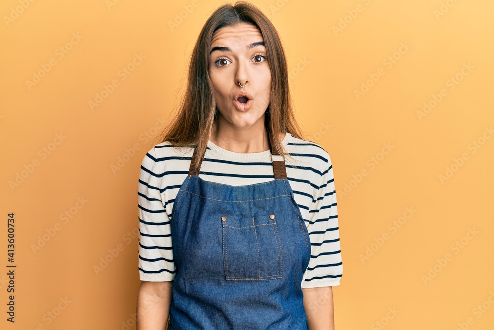 Young hispanic woman wearing barber apron scared and amazed with open mouth for surprise, disbelief face Young hispanic woman wearing barber apron scared and amazed with open mouth for surprise, disbelief face