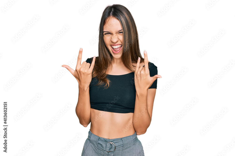 Young brunette woman wearing casual clothes shouting with crazy expression doing rock symbol with hands up. music star. heavy concept. Young brunette woman wearing casual clothes shouting with crazy expression doing rock symbol with hands up. music star. heavy concept.