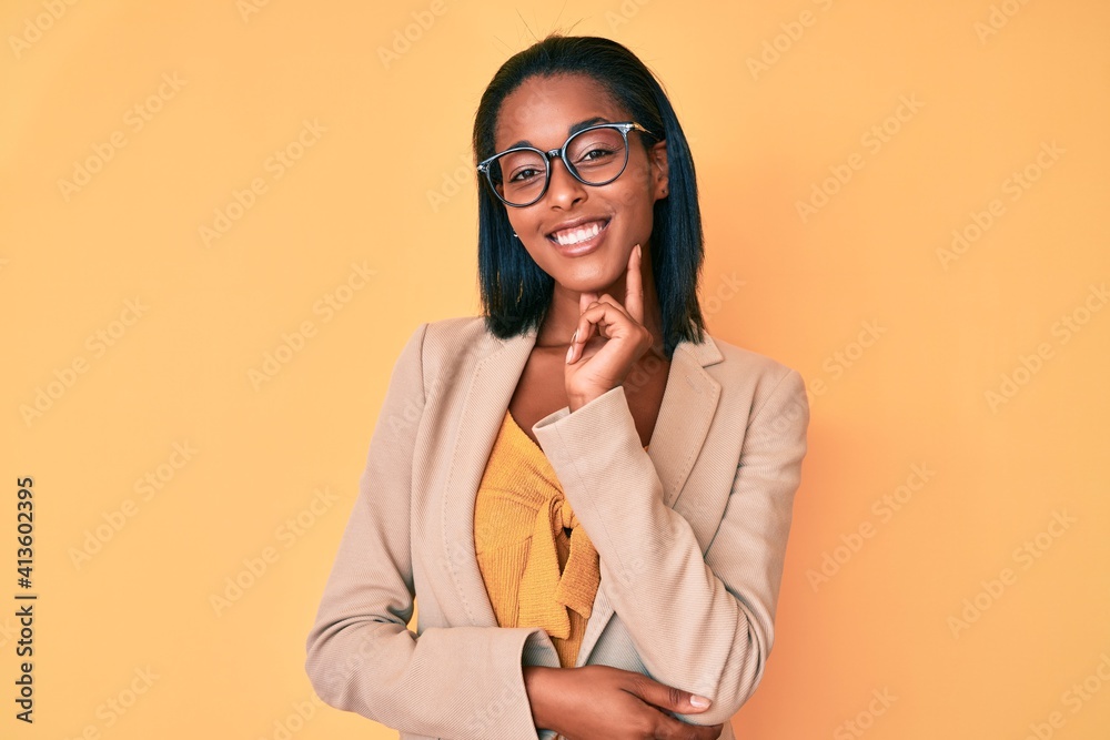 Young african american woman wearing business clothes looking confident at the camera with smile with crossed arms and hand raised on chin. thinking positive. Young african american woman wearing business clothes looking confident at the camera with smile with crossed arms and hand raised on chin. thinking positive.
