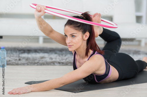 beautiful young woman practising hula hoop at home photo