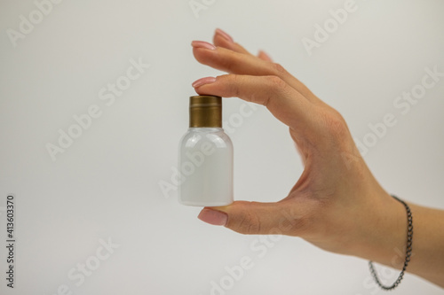 A womans hand is holding a bottle from hotel with body lotion