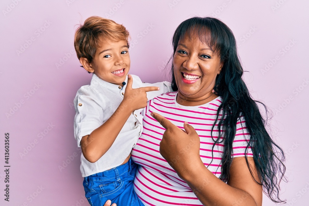 Hispanic family of mother and son hugging together with love smiling happy pointing with hand and finger Hispanic family of mother and son hugging together with love smiling happy pointing with hand and finger
