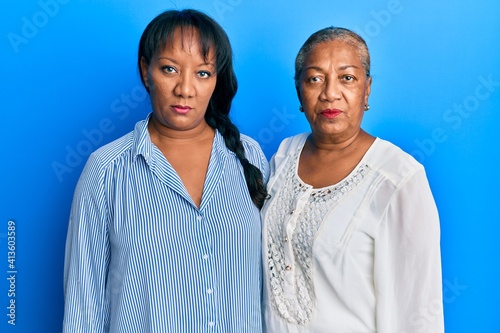 Hispanic family of mother and daughter hugging together with love thinking attitude and sober expression looking self confident