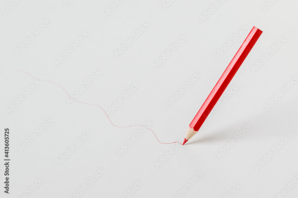 Red pencil drawing a line on a white background. Red pencil drawing a line on a white background.