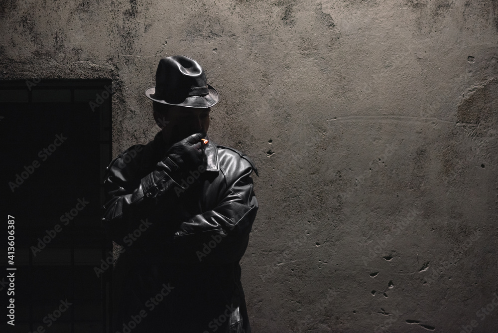 Detective spy agent is smoking a cigarette on a concrete wall background. Detective spy agent is smoking a cigarette on a concrete wall background.