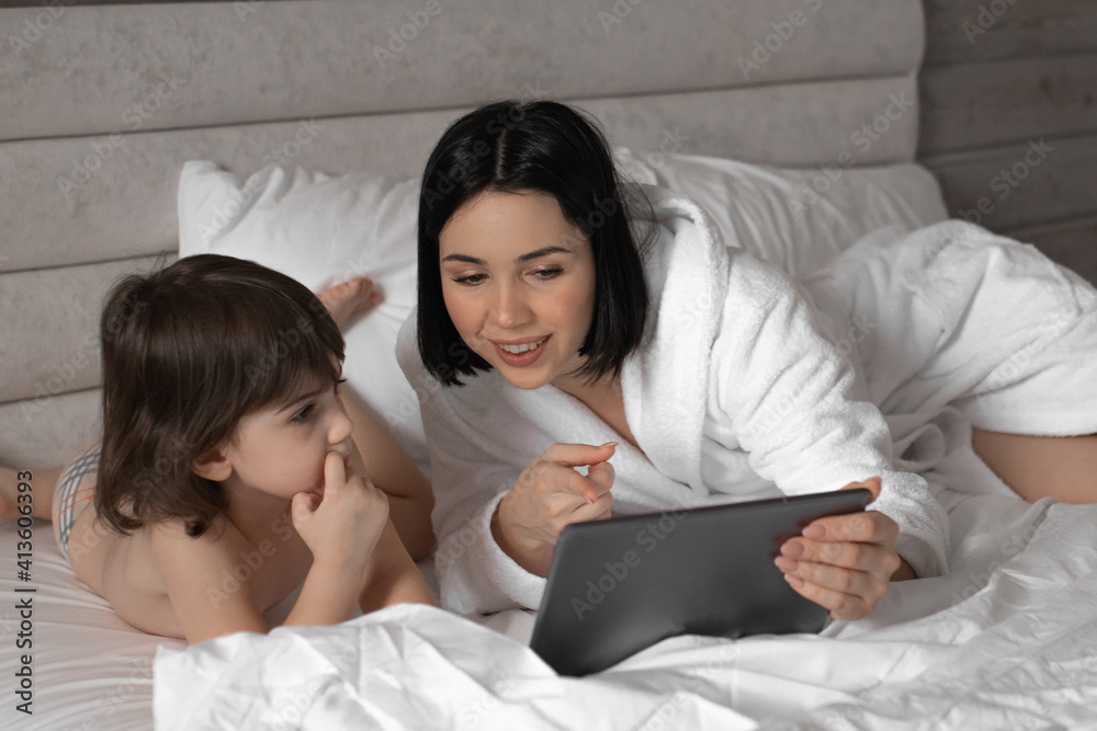 Young mother showing her daughter something on pad. Teaching and intertainment online. Young mother showing her daughter something on pad. Teaching and intertainment online.