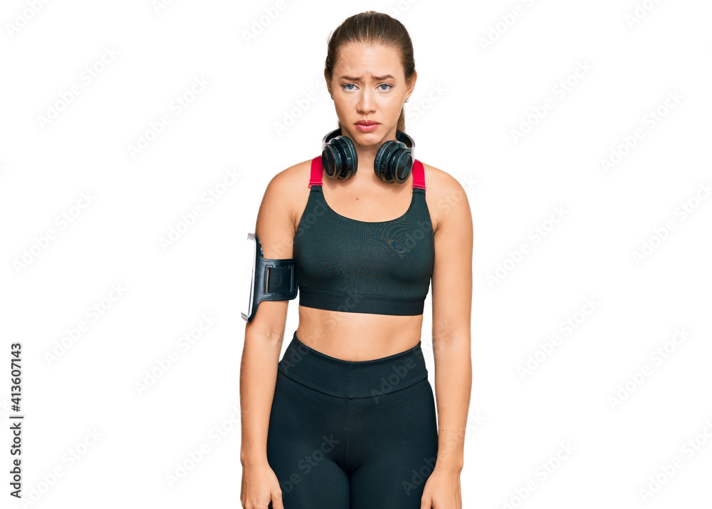 Beautiful blonde woman wearing gym clothes and using headphones skeptic and nervous, frowning upset because of problem. negative person. Beautiful blonde woman wearing gym clothes and using headphones skeptic and nervous, frowning upset because of problem. negative person.
