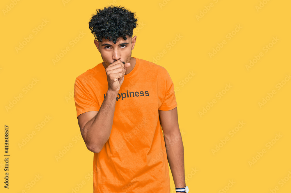 Young arab man wearing tshirt with happiness word message feeling unwell and coughing as symptom for cold or bronchitis. health care concept. Young arab man wearing tshirt with happiness word message feeling unwell and coughing as symptom for cold or bronchitis. health care concept.