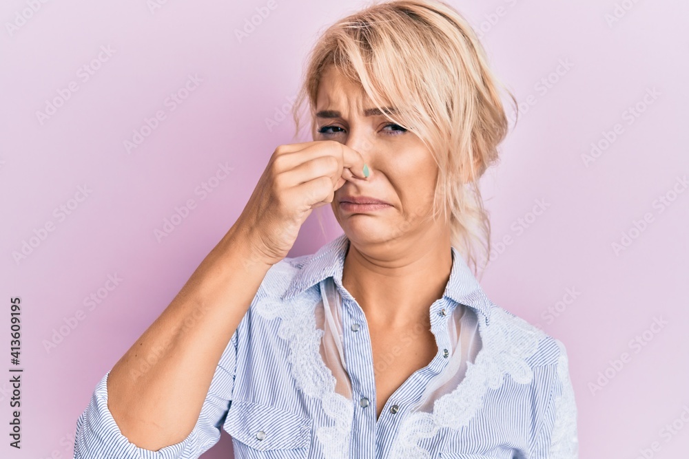 Young blonde girl wearing casual clothes smelling something stinky and disgusting, intolerable smell, holding breath with fingers on nose. bad smell Young blonde girl wearing casual clothes smelling something stinky and disgusting, intolerable smell, holding breath with fingers on nose. bad smell
