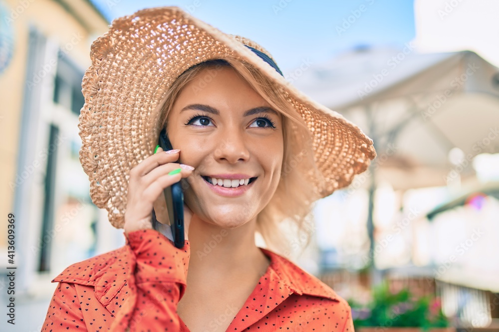 Young blonde tourist woman smiling happy talking on the smartphone at the city.