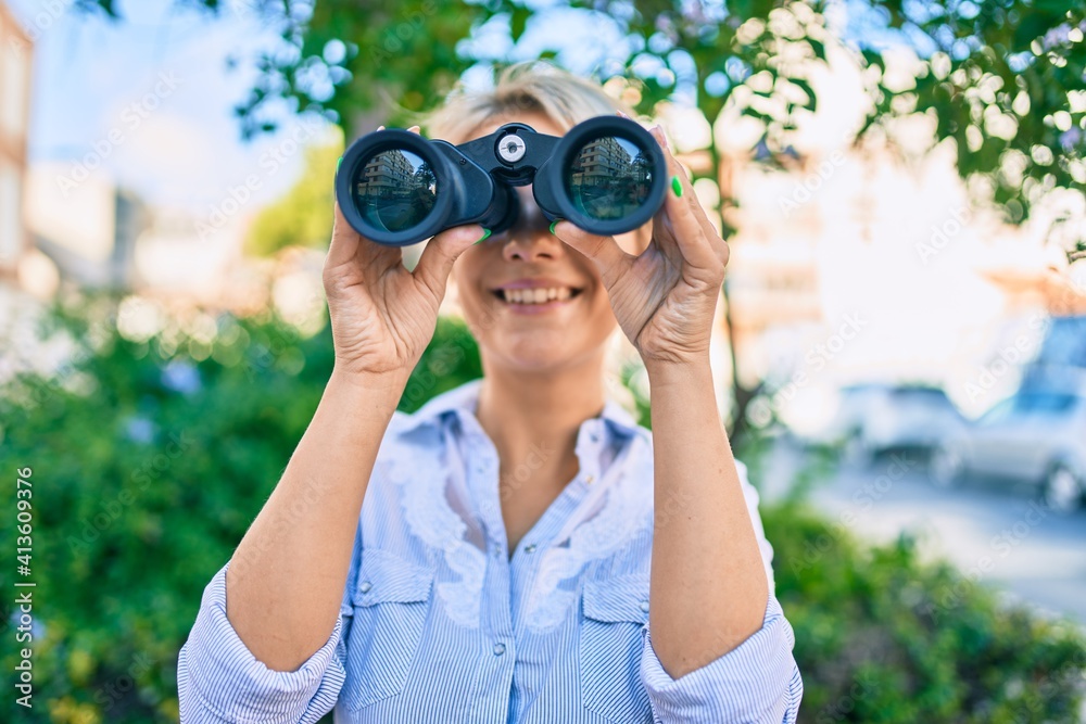 Young blonde woman smiling happy looking for new opportunity using binoculars at the park, Young blonde woman smiling happy looking for new opportunity using binoculars at the park,