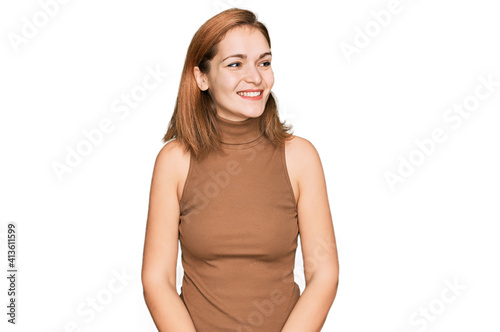 Young caucasian woman wearing casual clothes looking away to side with smile on face, natural expression. laughing confident.