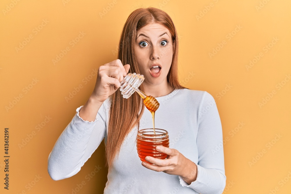 Young irish woman holding honey afraid and shocked with surprise and amazed expression, fear and excited face. Young irish woman holding honey afraid and shocked with surprise and amazed expression, fear and excited face.