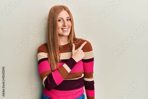 Young irish woman wearing casual clothes cheerful with a smile of face pointing with hand and finger up to the side with happy and natural expression on face