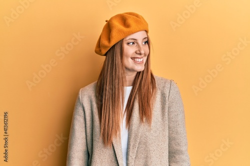 Young irish woman wearing french look with beret looking away to side with smile on face, natural expression. laughing confident.