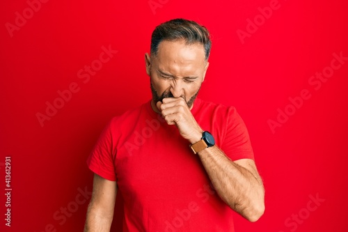 Handsome middle age man wearing casual red tshirt feeling unwell and coughing as symptom for cold or bronchitis. health care concept.