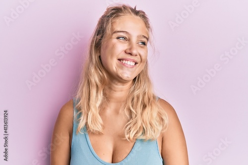 Young blonde girl wearing casual clothes looking away to side with smile on face  natural expression. laughing confident.