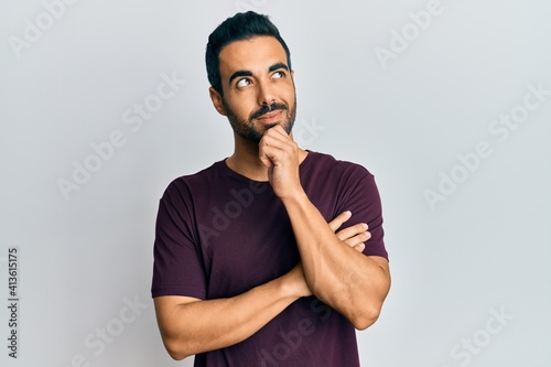 Young hispanic man wearing casual clothes thinking concentrated about doubt with finger on chin and looking up wondering