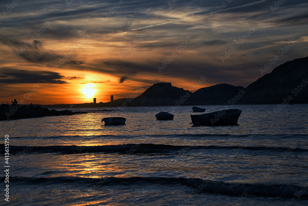 beautiful sunset on the beach with boats and very colorful on the beach of Alicante, Spain