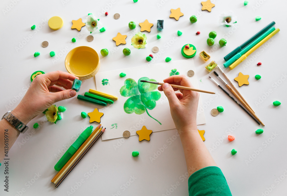 Drawing a green lucky clover st. Patrick. Top view of the hands. Saint Patrick's Day concept. Drawing a green lucky clover st. Patrick. Top view of the hands. Saint Patrick's Day concept.