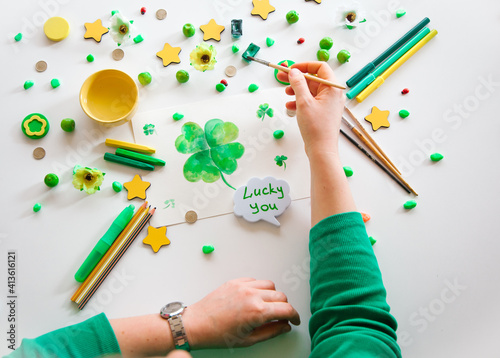 Drawing a green lucky clover st. Patrick. Top view of the hands.  Saint Patrick's Day concept.