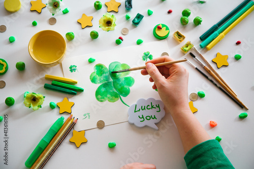 Drawing a green lucky clover st. Patrick. Top view of the hands.  Saint Patrick's Day concept.