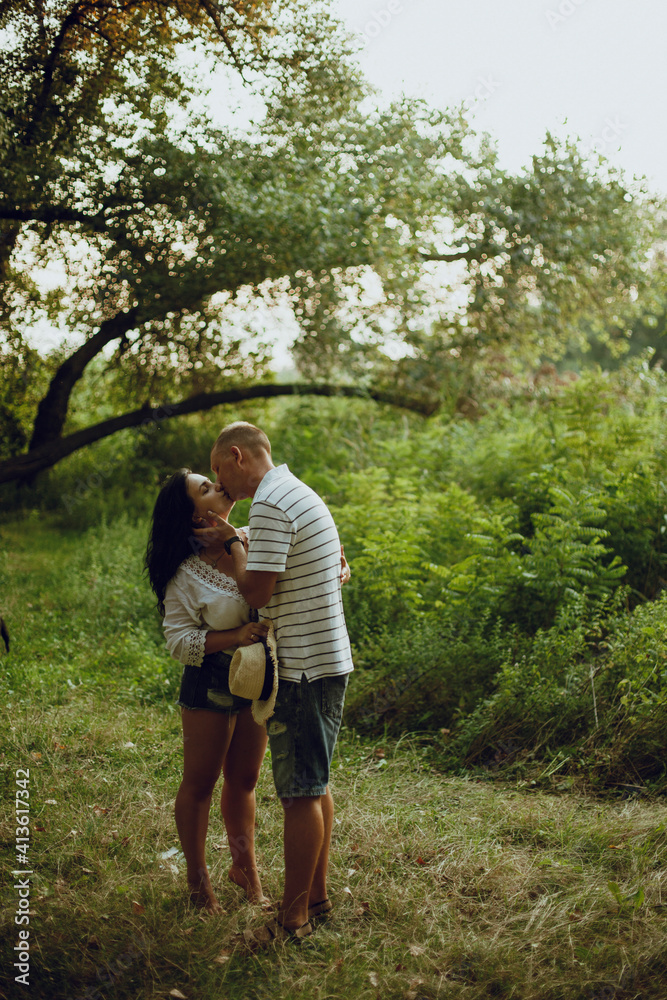 couple in love hugging and kissing in the park in the forest couple in love hugging and kissing in the park in the forest