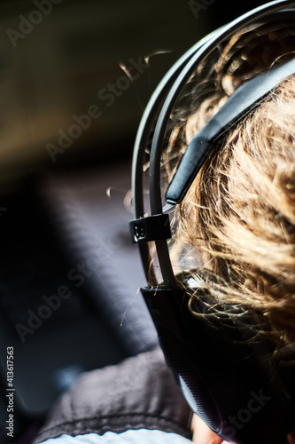 A woman working on a laptop and has headphones on