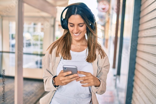 Young caucasian woman smiling happy using smartphone and headphones at the city.