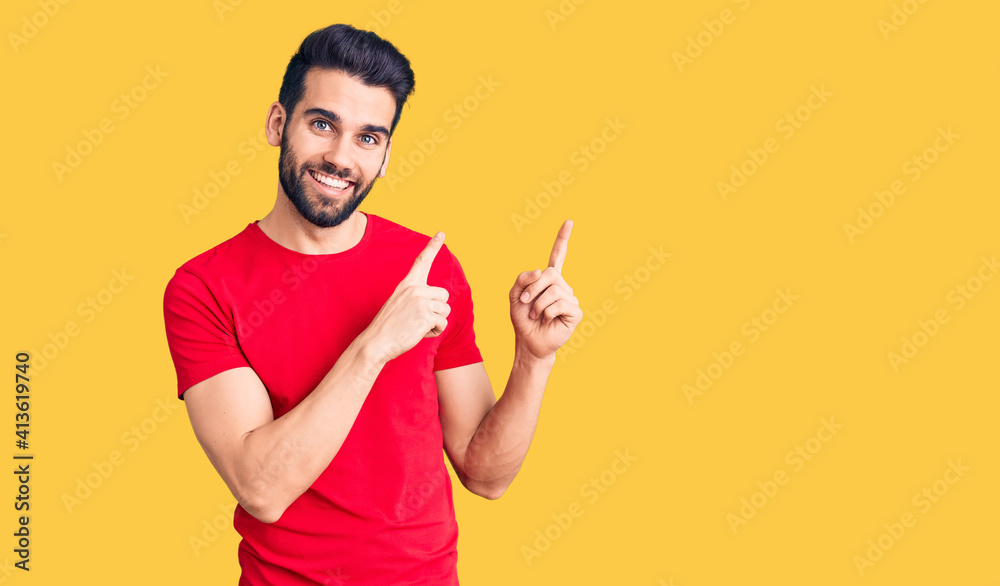 Young handsome man with beard wearing casual t-shirt smiling and looking at the camera pointing with two hands and fingers to the side. Young handsome man with beard wearing casual t-shirt smiling and looking at the camera pointing with two hands and fingers to the side.