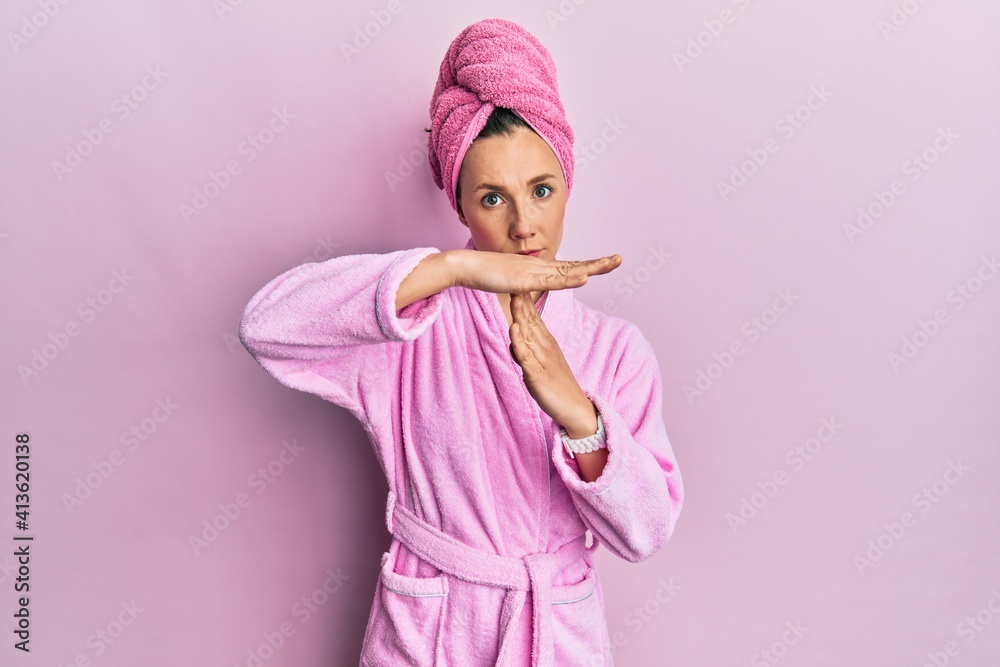 Young blonde woman wearing shower towel cap and bathrobe doing time out gesture with hands, frustrated and serious face Young blonde woman wearing shower towel cap and bathrobe doing time out gesture with hands, frustrated and serious face