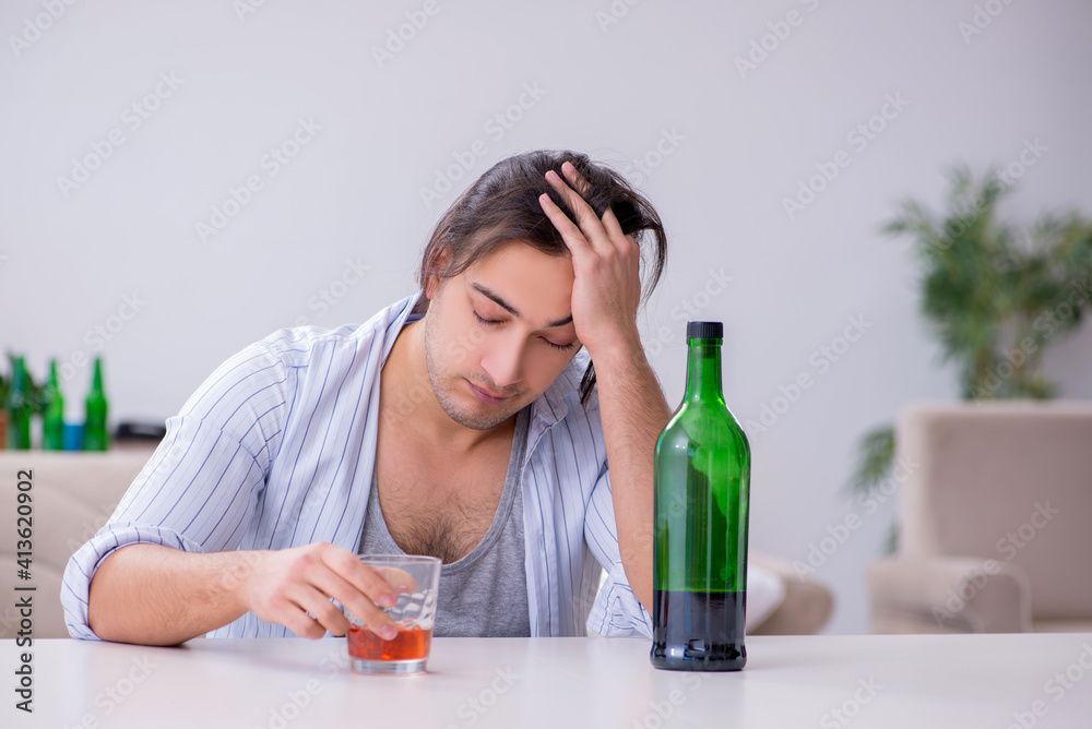 Young male alcoholic drinking whiskey at home Young male alcoholic drinking whiskey at home