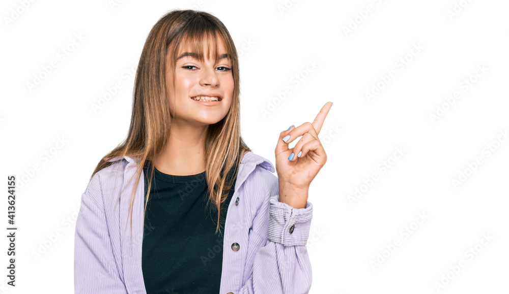 Teenager caucasian girl wearing casual clothes with a big smile on face, pointing with hand and finger to the side looking at the camera. Teenager caucasian girl wearing casual clothes with a big smile on face, pointing with hand and finger to the side looking at the camera.
