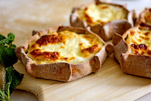 Rye dough pies with potato filling. National Karelian food wicket close-up on a wooden board. Alternative flour baked goods without sugar and gluten, authentic baked goods