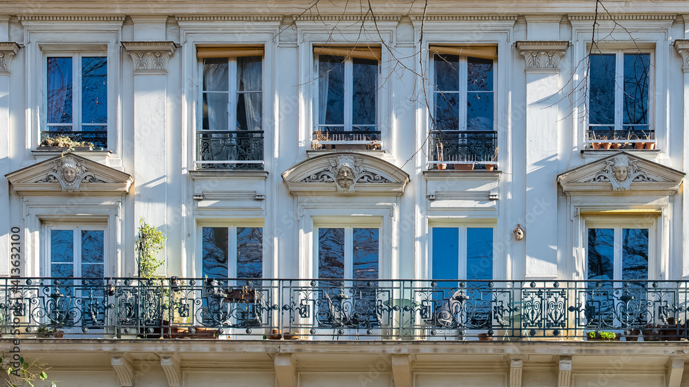 Paris, typical facade, beautiful building, with heads sculpted above the windows
