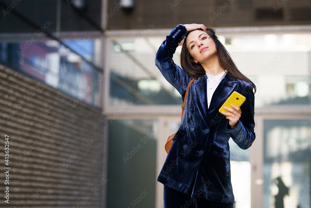 Fototapeta premium Business woman wearing blue suit using smartphone in an office building.