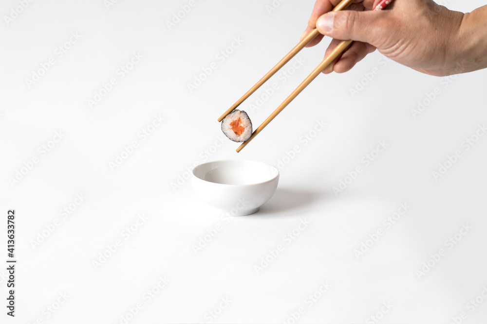 Man's hand picking up sushi with chopsticks and dipping in soy sauce. Man's hand picking up sushi with chopsticks and dipping in soy sauce.